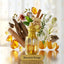 Baccarat Rouge perfume bottle surrounded by spices and flowers on a reflective surface.