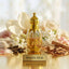 Gold perfume bottle labeled 'White Oud' surrounded by flowers, oud sticks and cinnamon sticks on a light background